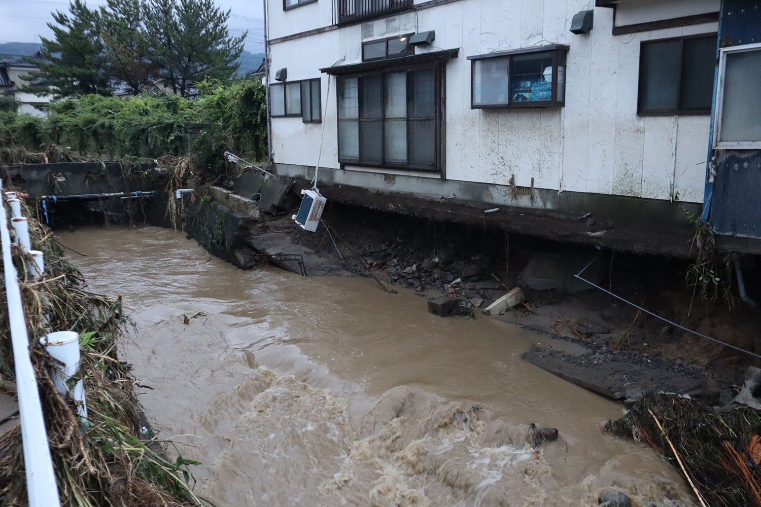 日本秋田县周四的暴雨，导致仁贺保市一栋房屋的地基在洪水冲刷下崩塌。 （图取自时事通讯社/法新社）