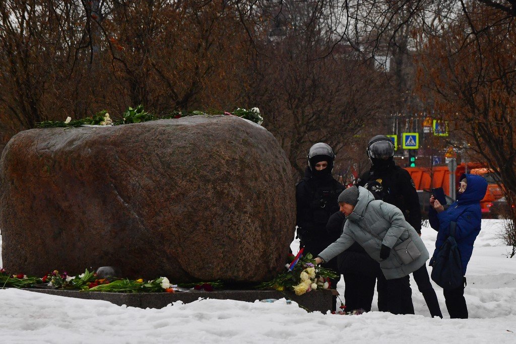 圣彼得堡警察在政治镇压受害者索洛维茨基纪念碑前，监控献花悼念纳瓦尔尼的民众。（图取自法新社）